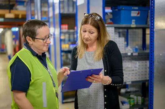 A warehouse worker in a safety vest reviewing an incident report with a supervisor, representing a workers' compensation claim in Illinois